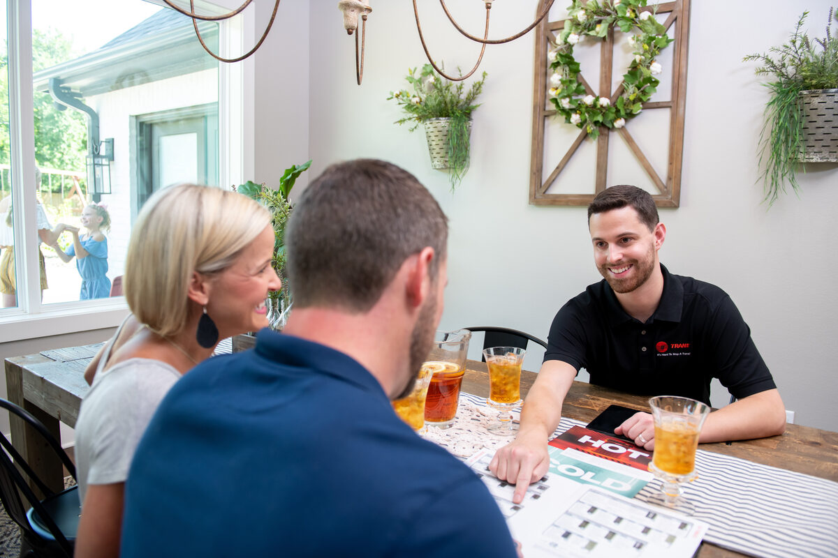 HVAC technician speaking with homeowners at a kitchen table